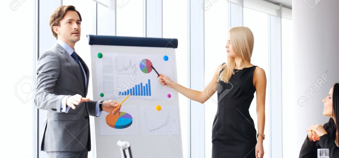 Workers at business meeting looking at presentation of financial reports in modern office